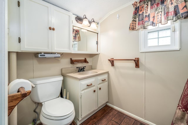 bathroom with baseboards, toilet, vanity, a textured ceiling, and wood finished floors