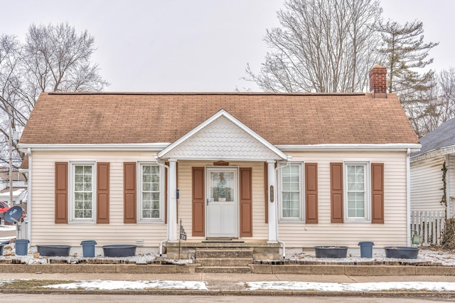 view of front of house with crawl space, a chimney, and a shingled roof