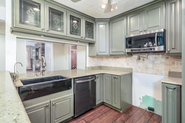 kitchen featuring a ceiling fan, appliances with stainless steel finishes, a sink, decorative backsplash, and glass insert cabinets