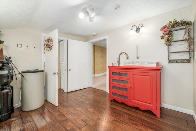 interior space featuring a sink, wood finished floors, baseboards, a textured ceiling, and lofted ceiling