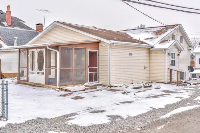 snow covered rear of property with a chimney