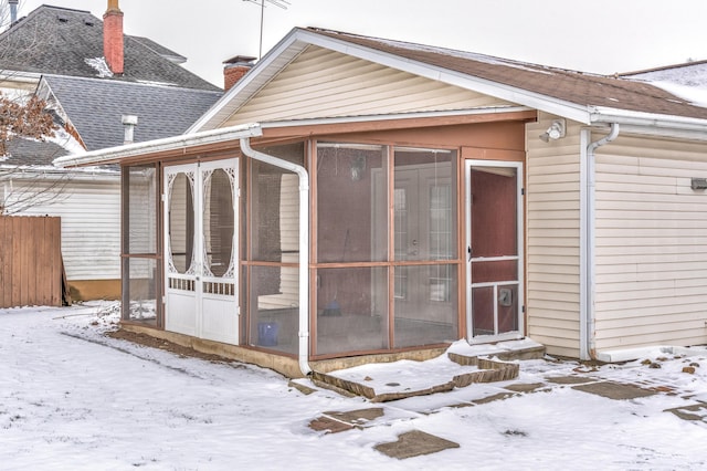 snow covered property with a sunroom and fence