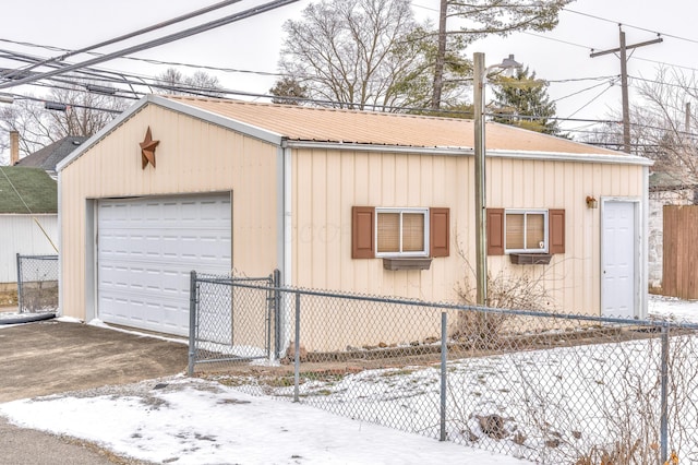 snow covered garage with fence and a garage