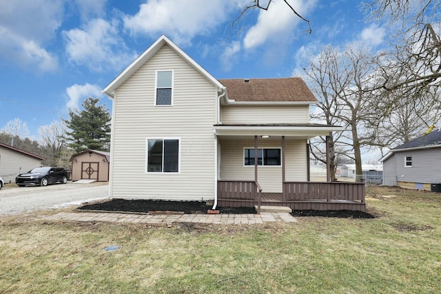 rear view of house with a porch, a shed, and a lawn