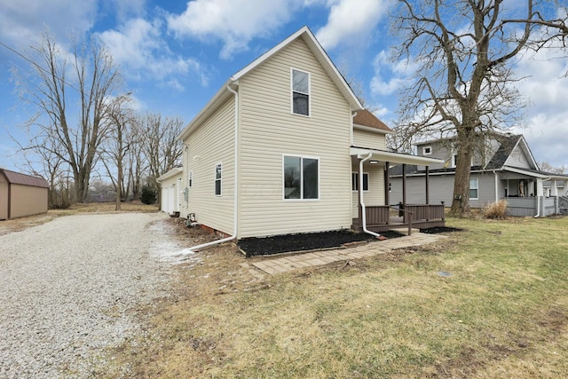 back of property featuring a garage, a yard, and covered porch