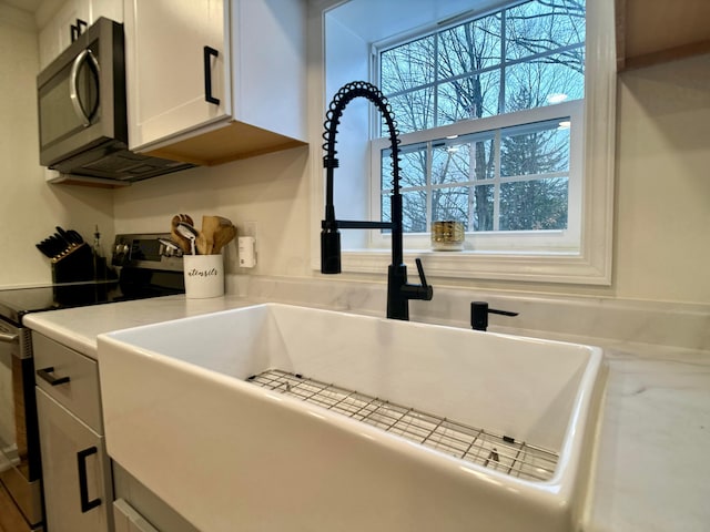 interior details featuring white cabinetry, sink, and stainless steel appliances