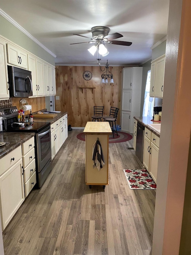 kitchen featuring crown molding, appliances with stainless steel finishes, wood-type flooring, and a kitchen island