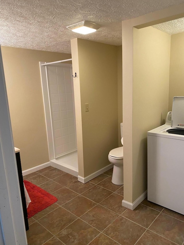 bathroom featuring tile patterned flooring, washer / dryer, toilet, and walk in shower