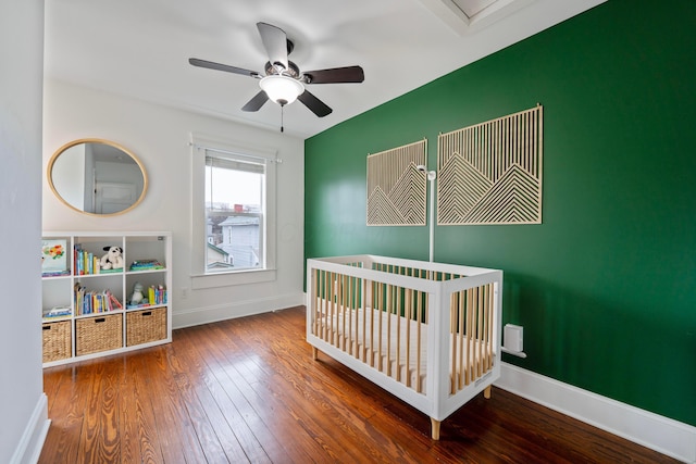 bedroom featuring hardwood / wood-style flooring, a nursery area, and ceiling fan