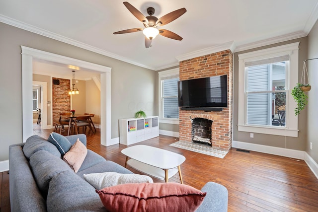 living room with crown molding, ceiling fan, wood-type flooring, and a brick fireplace