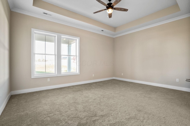 carpeted spare room with baseboards, visible vents, a ceiling fan, ornamental molding, and a tray ceiling