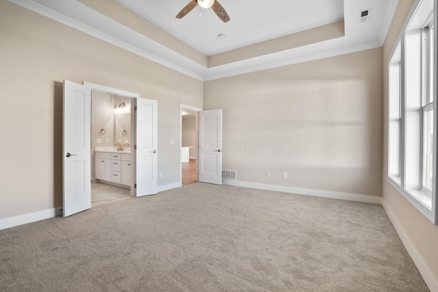 unfurnished bedroom with light carpet, a raised ceiling, visible vents, and baseboards