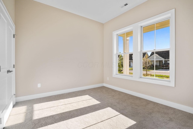 spare room with carpet floors, baseboards, and visible vents