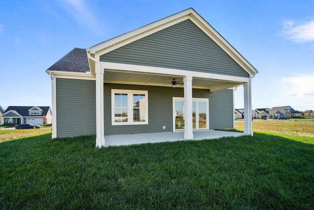 rear view of house featuring a patio, a ceiling fan, a yard, roof with shingles, and a residential view