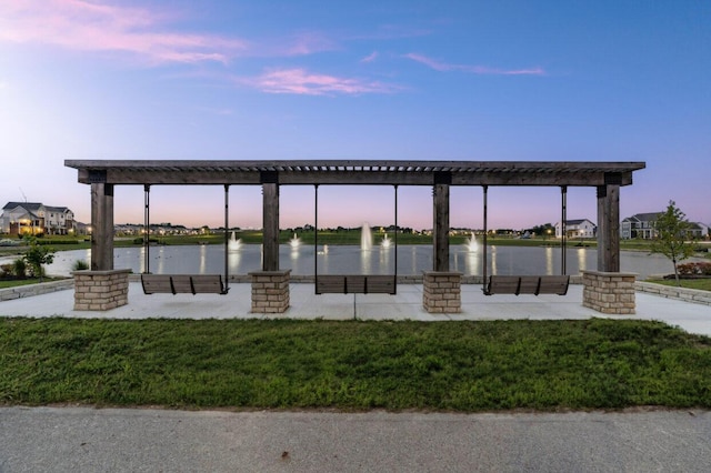 view of property's community with a water view, a pergola, and a yard