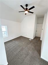 additional living space featuring ceiling fan, lofted ceiling, and dark carpet