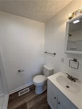 bathroom featuring hardwood / wood-style flooring, vanity, a textured ceiling, and toilet