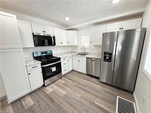 kitchen with white cabinetry, appliances with stainless steel finishes, sink, and light hardwood / wood-style floors