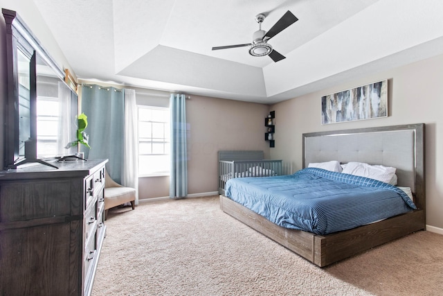 carpeted bedroom featuring a raised ceiling and ceiling fan