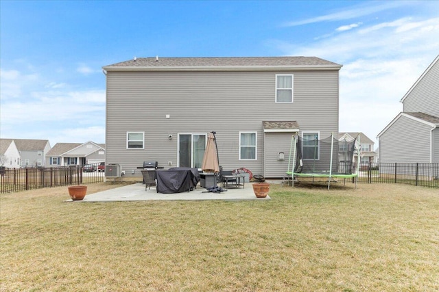 rear view of property with a patio, a yard, and a trampoline