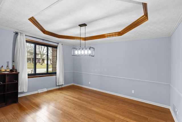 unfurnished dining area with crown molding, wood-type flooring, a raised ceiling, and a textured ceiling