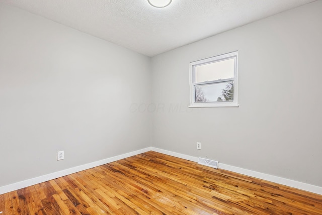 spare room with light hardwood / wood-style flooring and a textured ceiling