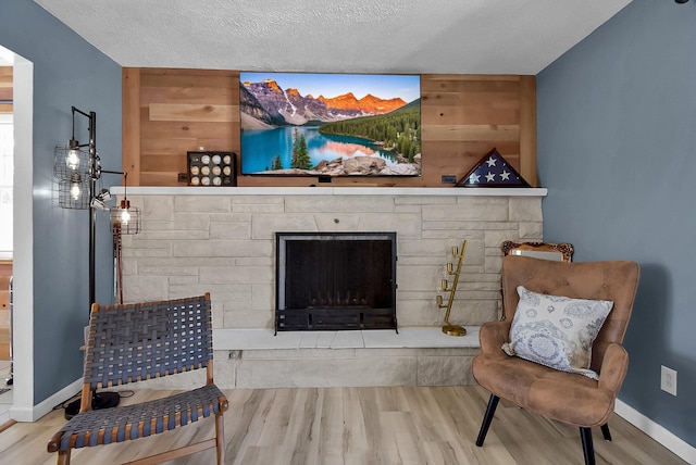 living area featuring hardwood / wood-style flooring, wooden walls, a textured ceiling, and a fireplace