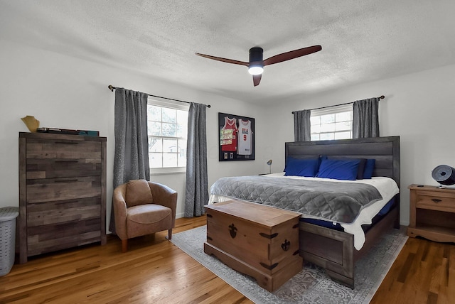 bedroom with ceiling fan, hardwood / wood-style floors, and a textured ceiling