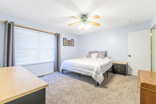 carpeted bedroom featuring ceiling fan and a textured ceiling