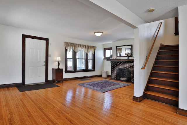 foyer entrance with a brick fireplace and light hardwood / wood-style floors