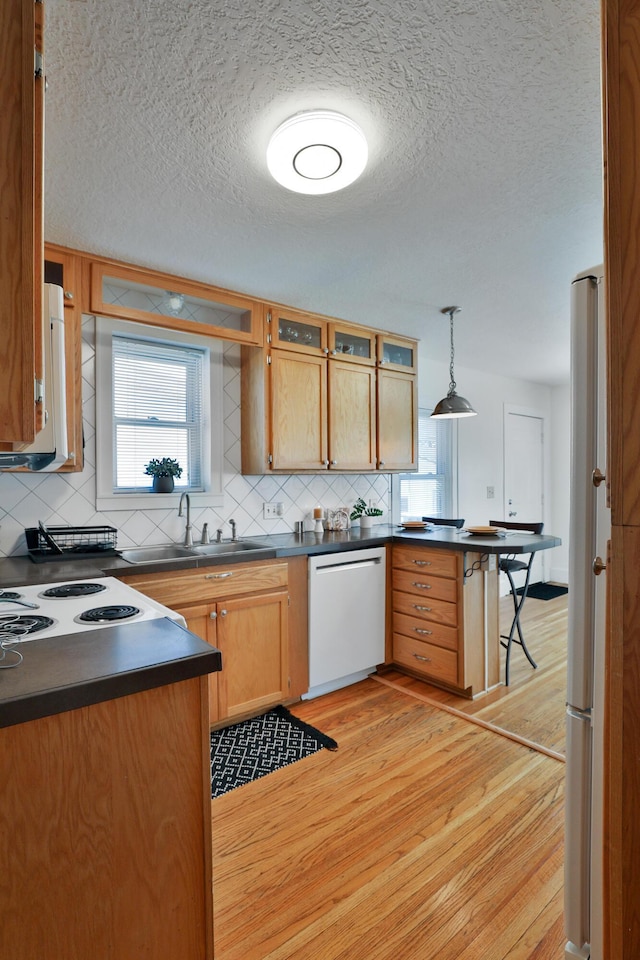 kitchen featuring pendant lighting, sink, backsplash, white appliances, and light hardwood / wood-style flooring