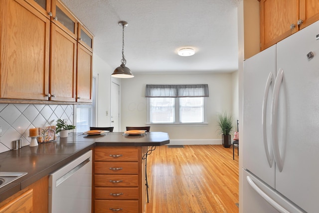 kitchen with white appliances, hanging light fixtures, tasteful backsplash, light hardwood / wood-style floors, and kitchen peninsula