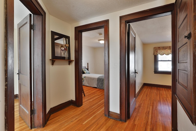 corridor with light hardwood / wood-style floors and a textured ceiling