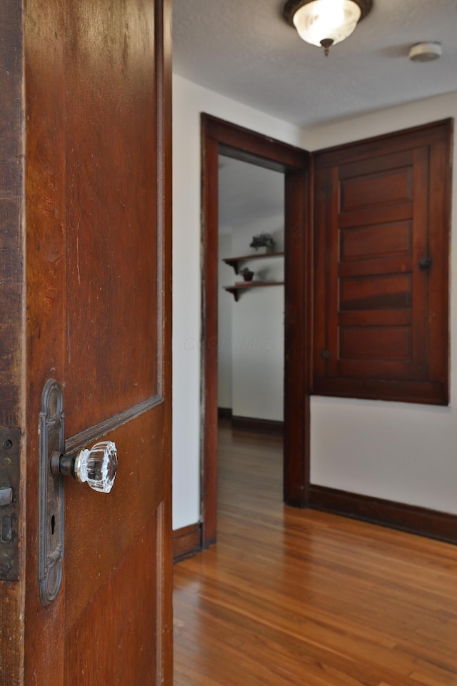 corridor with hardwood / wood-style flooring