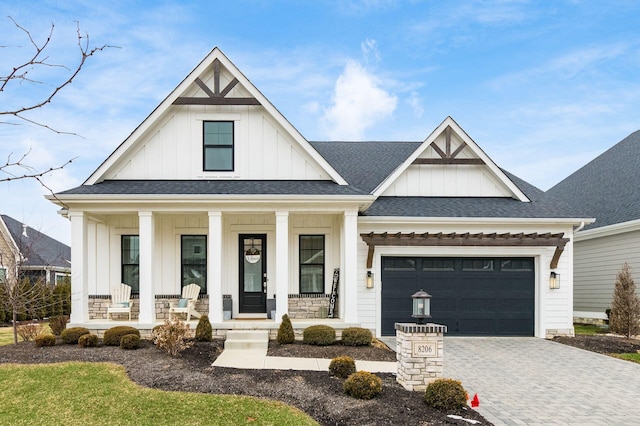 modern farmhouse style home with decorative driveway, a porch, a shingled roof, an attached garage, and board and batten siding