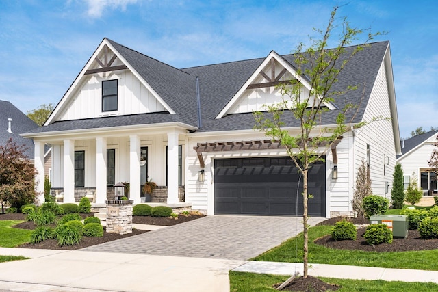 view of front of property with roof with shingles, an attached garage, board and batten siding, a porch, and decorative driveway