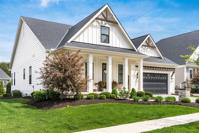 modern inspired farmhouse featuring board and batten siding, a porch, roof with shingles, a front yard, and a garage