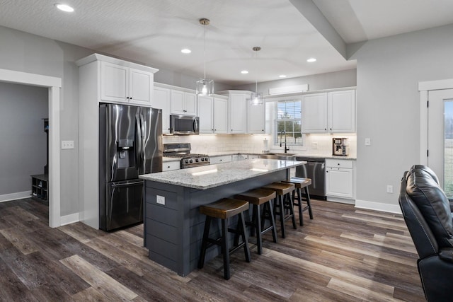 kitchen with white cabinetry, backsplash, hanging light fixtures, a center island, and stainless steel appliances