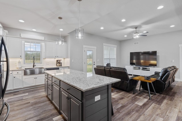 kitchen featuring pendant lighting, sink, white cabinets, hardwood / wood-style flooring, and a center island