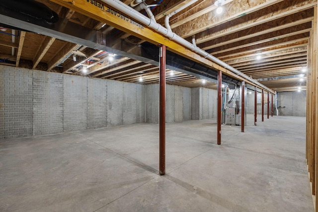 basement featuring brick wall and heating unit