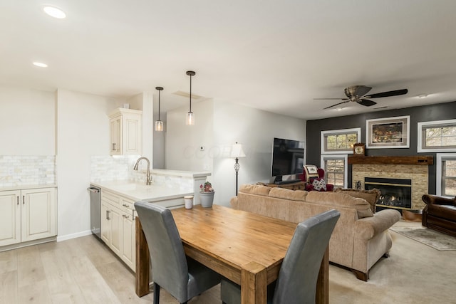 dining space featuring ceiling fan, sink, and light wood-type flooring