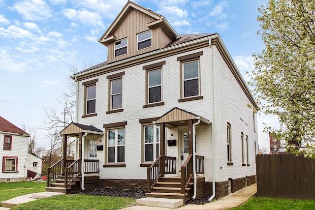 view of front facade featuring brick siding and fence