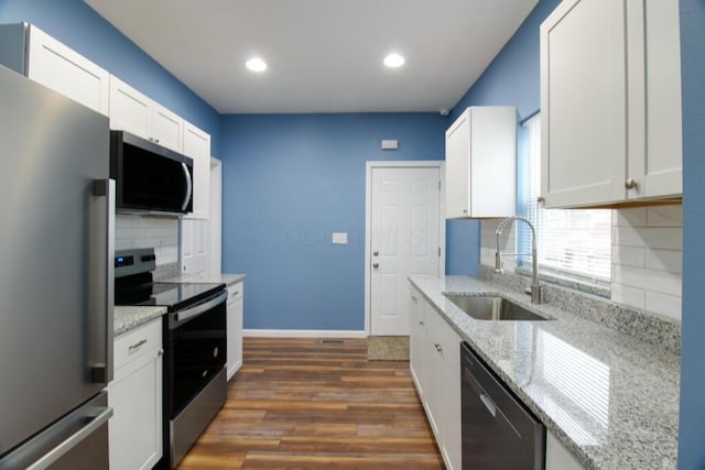 kitchen featuring appliances with stainless steel finishes, sink, white cabinets, dark hardwood / wood-style flooring, and light stone counters