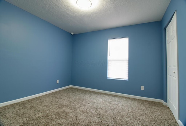 carpeted spare room featuring a textured ceiling