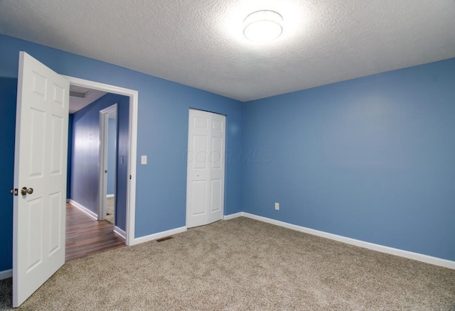 unfurnished bedroom with carpet flooring, a textured ceiling, and a closet