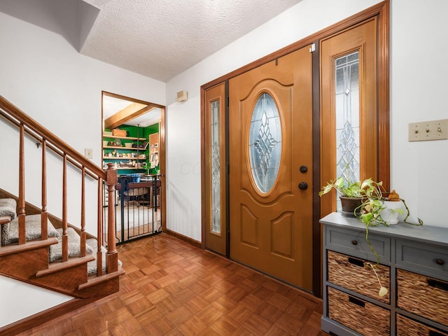 foyer featuring parquet floors, beam ceiling, and a textured ceiling