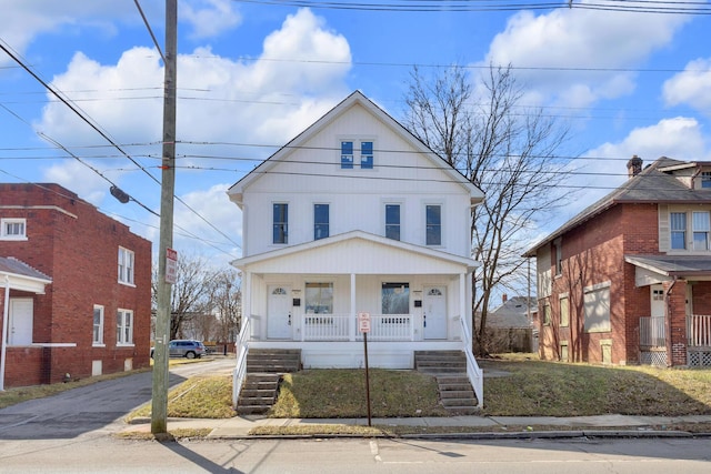 traditional style home with covered porch, stairway, and aphalt driveway