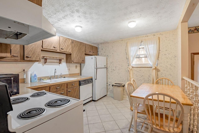 kitchen with wallpapered walls, white appliances, light countertops, a sink, and exhaust hood