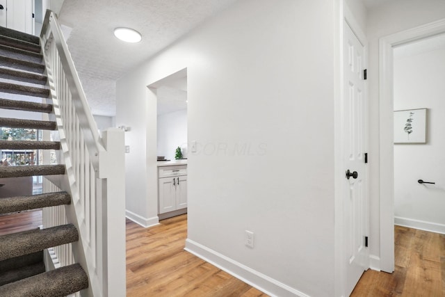 stairs featuring a textured ceiling and wood-type flooring