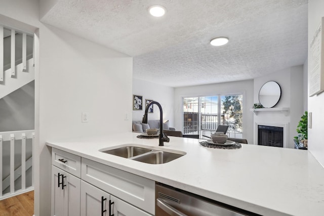 kitchen with sink, white cabinetry, dishwasher, a textured ceiling, and kitchen peninsula